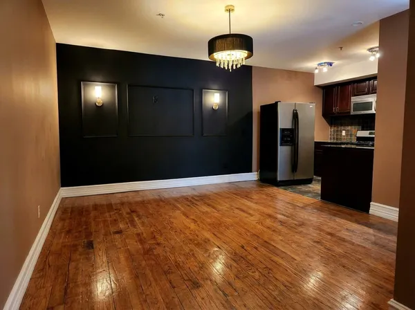 a view of an empty room with kitchen and a window