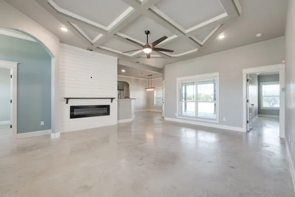 a view of an empty room with a fireplace and a ceiling fan