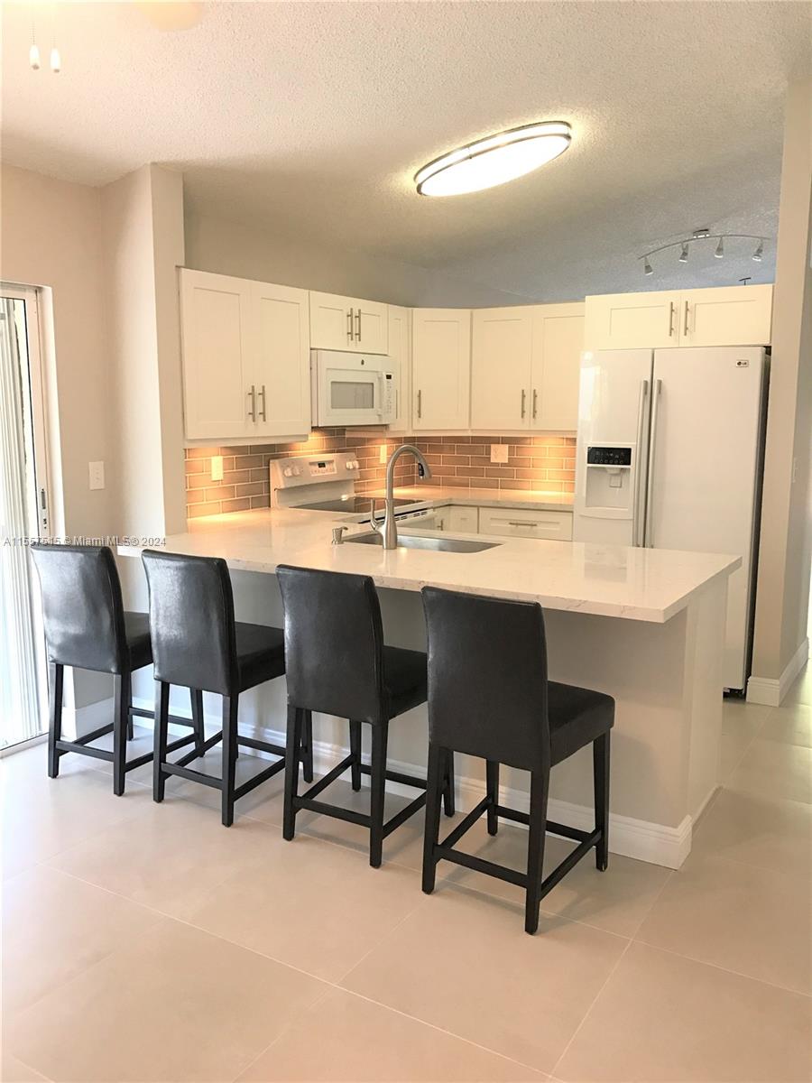 a kitchen with stainless steel appliances granite countertop a table chairs sink and white cabinets