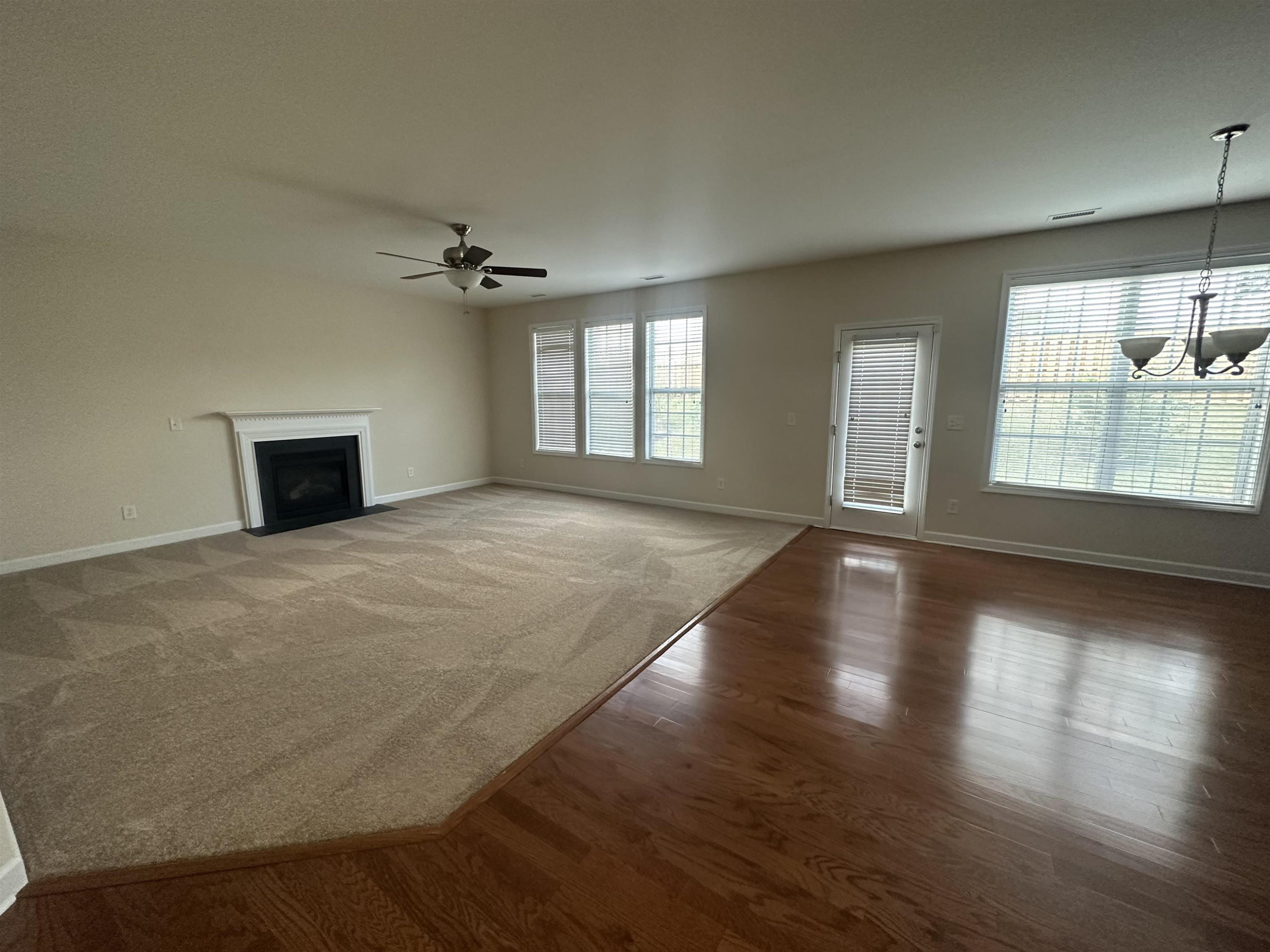 5161 Holly Ridge Farm Road Raleigh, NC 27616 - Photo 7 of 35 an empty room with wooden floor chandelier and windows