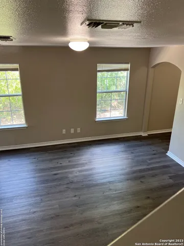 an empty room with wooden floor and windows