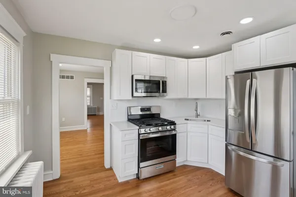 a kitchen with granite countertop a refrigerator stove and wooden floor