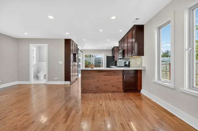 a large kitchen with stainless steel appliances granite countertop a large counter top and a wooden floors