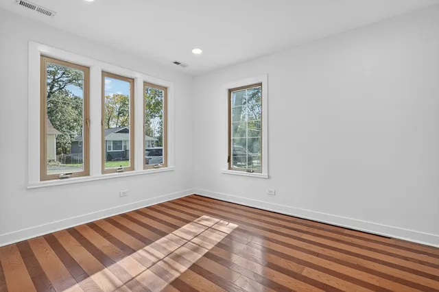 a view of an empty room with a window and wooden floor