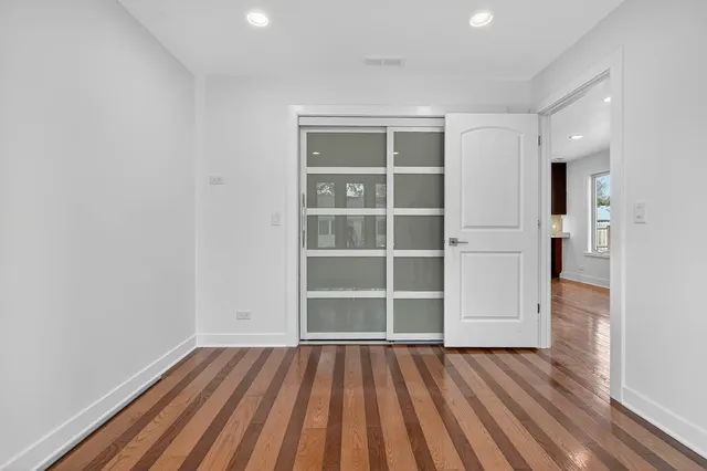 a view of an empty room with wooden floor and closet