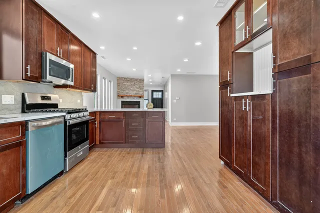 a large kitchen with stainless steel appliances granite countertop wooden floors a stove and a sink