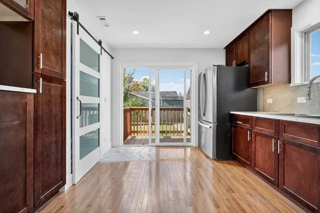 a kitchen with stainless steel appliances granite countertop a refrigerator oven a sink with wooden cabinets and wooden floor