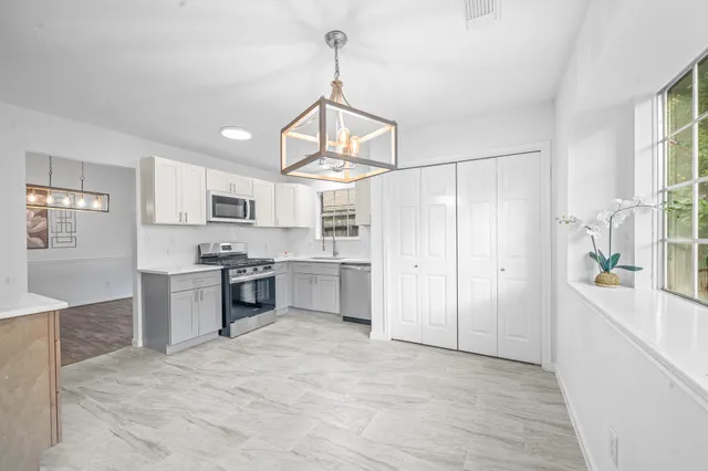 an empty room with wooden floor cabinet and windows