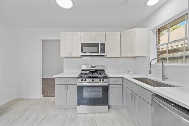 a kitchen with stainless steel appliances white cabinets and stove top oven