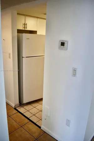a view of a refrigerator in kitchen and an empty room