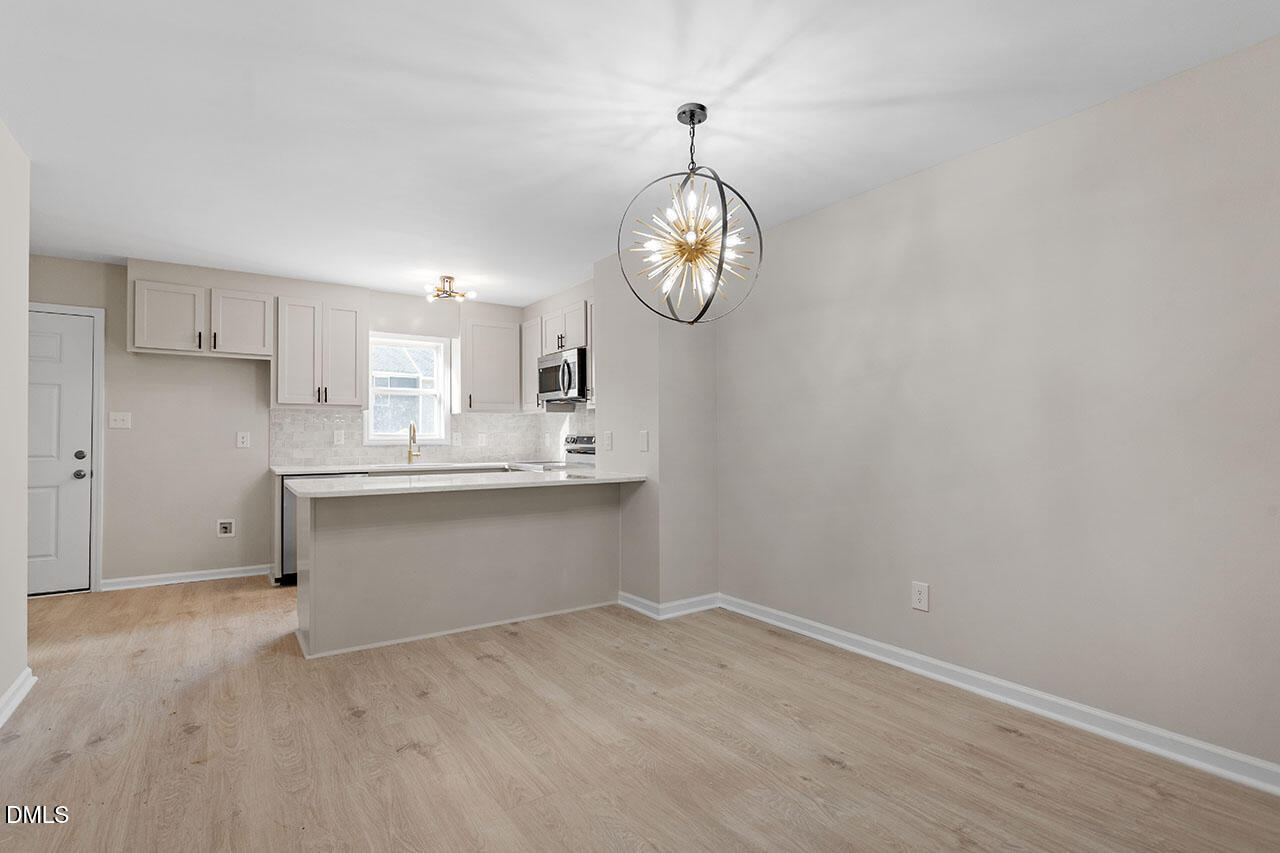 389 East Williams Street Angier, NC 27501 - Photo 21 of 29 an empty room with kitchen view and wooden floor