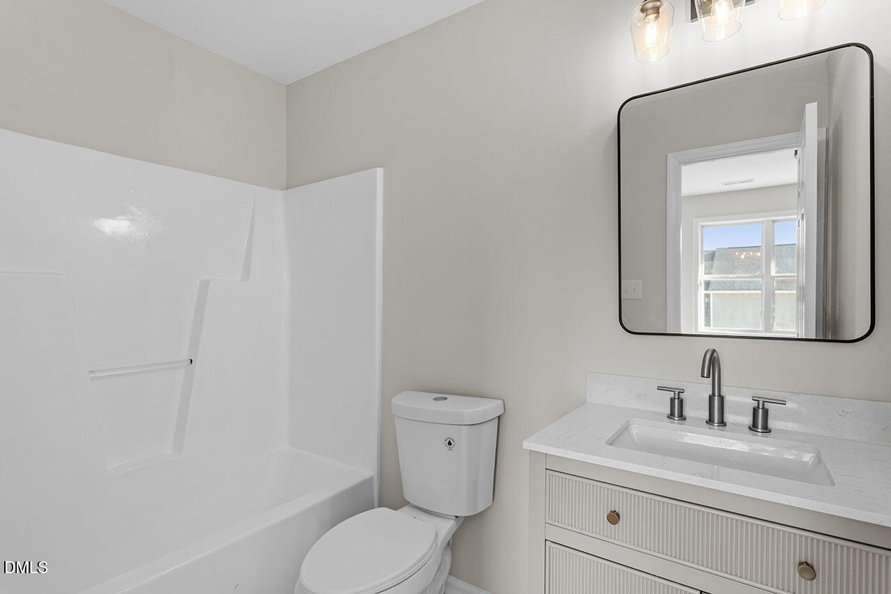 389 East Williams Street Angier, NC 27501 - Photo 25 of 29 a bathroom with a toilet a sink a mirror and vanity
