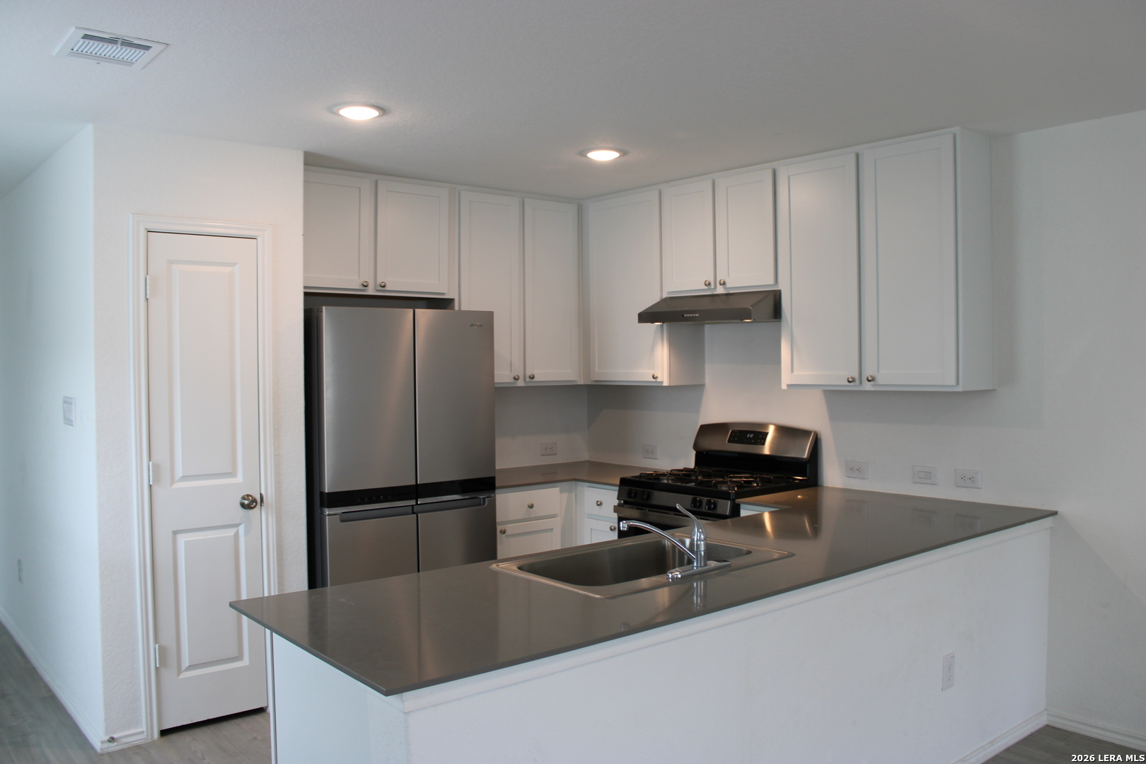 124 Horseshoe Trail Pleasanton, TX 78064 - Photo 4 of 16 a kitchen with stainless steel appliances granite countertop a refrigerator a sink a stove and white cabinets
