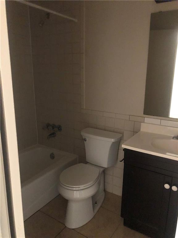 7007 Guadalupe Street, Unit 1 Austin, TX 78752 - Photo 4 of 8 Full bath with tile walls, tile patterned flooring, vanity, shower / bathtub combination, and a wainscoted wall