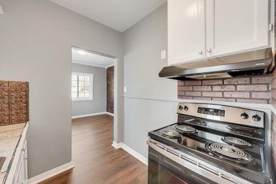 930 Freeman Street Sherman, TX 75092 - Photo 9 of 18 Kitchen space featuring a stainless steel electric range with an overhead vent hood, white cabinetry, and a brick-patterned backsplash