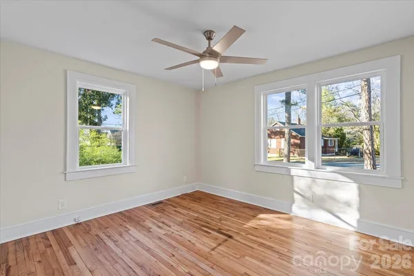 a view of an empty room with wooden floor and a window