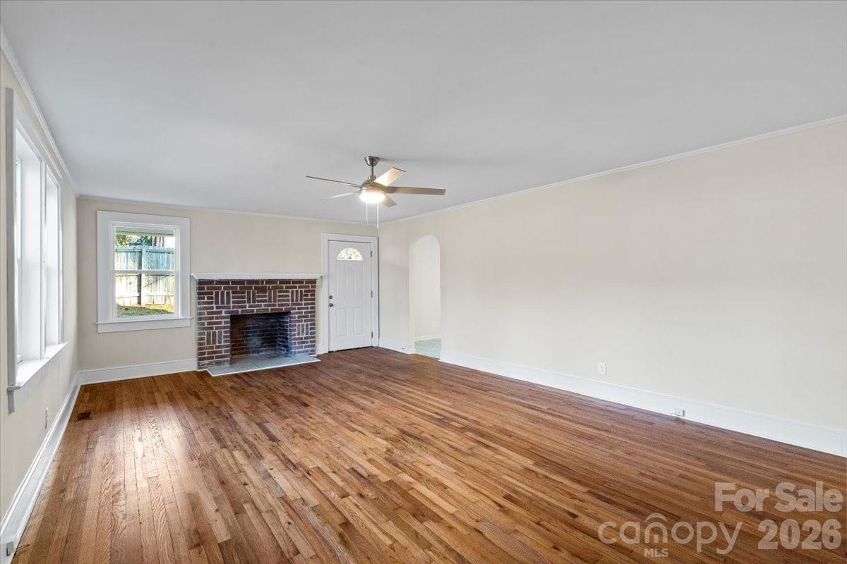 165 East Lacy Street Chester, SC 29706 - Photo 3 of 16 an empty room with wooden floor fireplace and windows