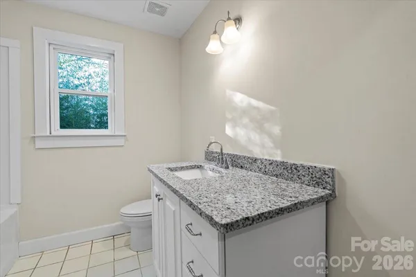 a bathroom with a granite countertop sink and a toilet
