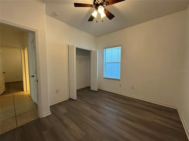 an empty room with wooden floor fan and windows