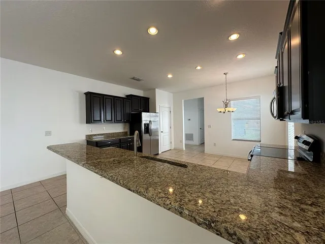 a kitchen with stainless steel appliances granite countertop a sink a stove and a refrigerator with wooden floor