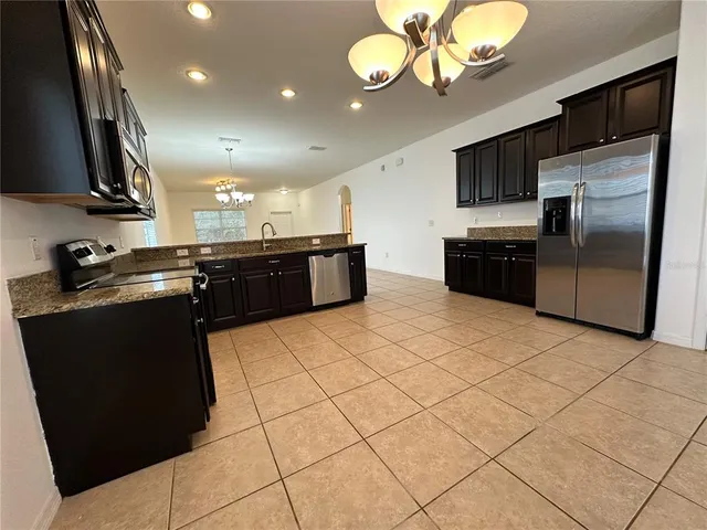 a kitchen with stainless steel appliances granite countertop a sink a stove and a refrigerator