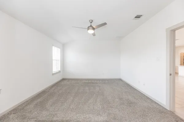 an empty room with a window and ceiling fan
