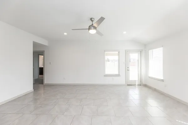 an empty room with windows and ceiling fan