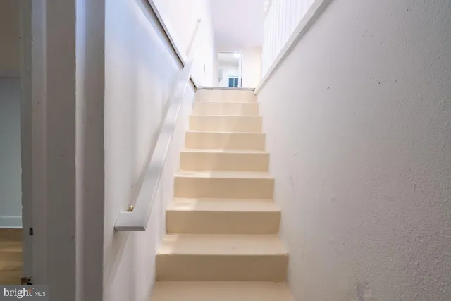 a view of staircase with white walls and white door