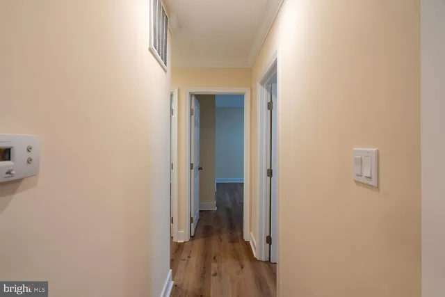 a view of a hallway with wooden floor and a bathroom