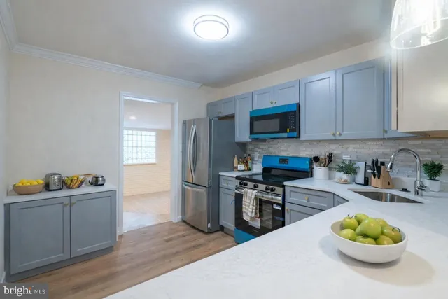 a kitchen with stainless steel appliances a stove a sink a refrigerator cabinets and a dining table