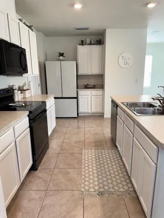 a kitchen with a sink a stove top oven and white cabinets