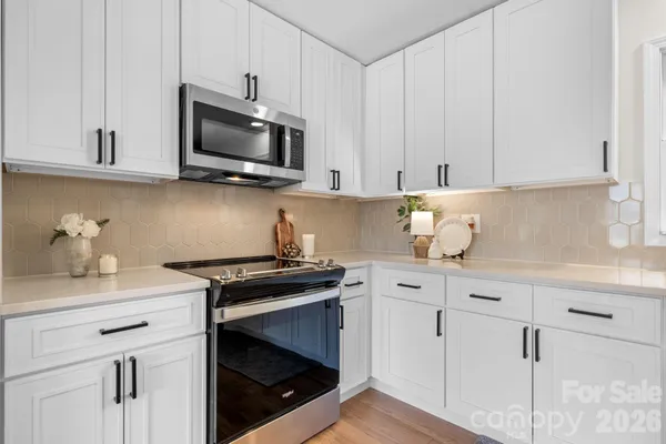 a kitchen with white cabinets and black appliances