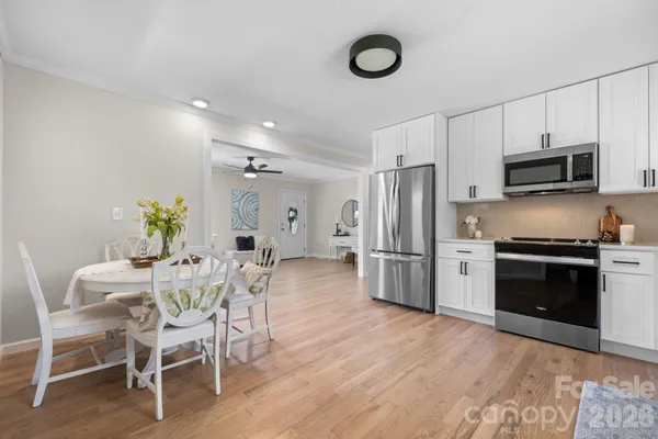 a kitchen with stainless steel appliances a dining table chairs stove refrigerator and microwave