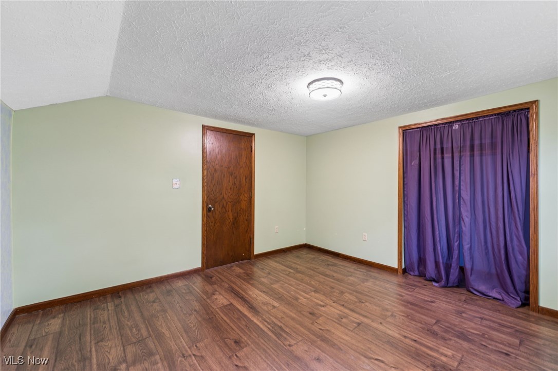 Empty room featuring dark wood finished floors and a textured ceiling