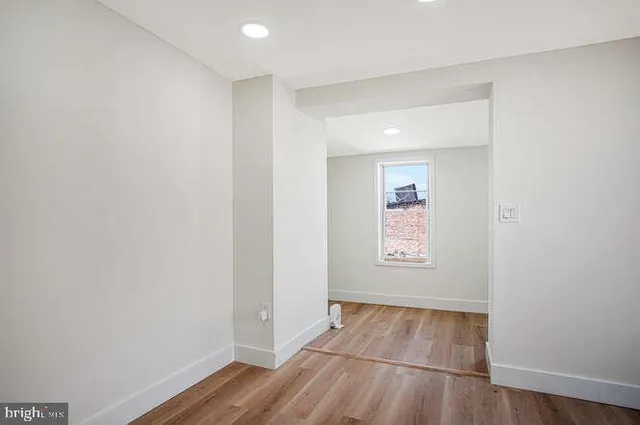 an empty room with wooden floor and window
