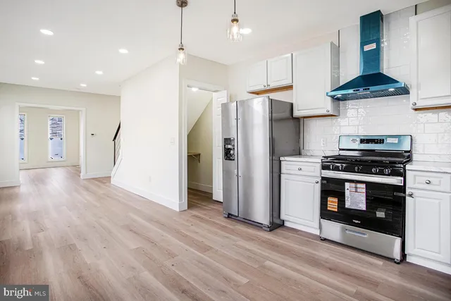 a kitchen with stainless steel appliances a stove a refrigerator and a wooden floor