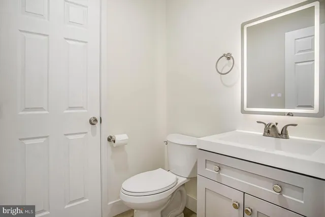a bathroom with a toilet a sink a mirror and vanity