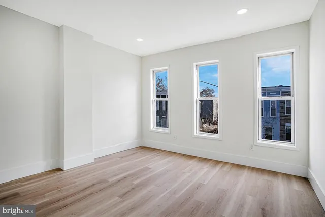 a view of an empty room with wooden floor and windows