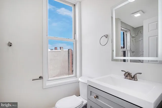 a bathroom with a sink vanity mirror and toilet