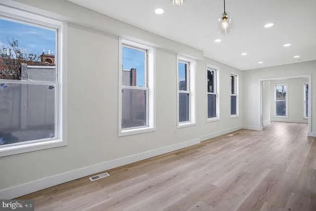 an empty room with wooden floor and windows