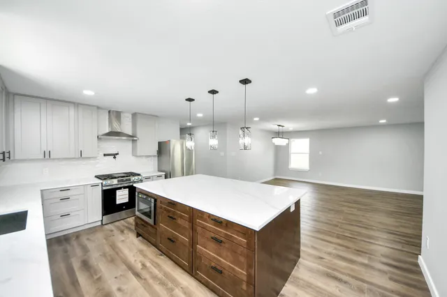 a kitchen with a stove a sink dishwasher and a refrigerator with wooden floor
