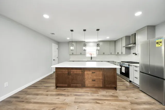 a large kitchen with stainless steel appliances granite countertop a sink a stove and a refrigerator