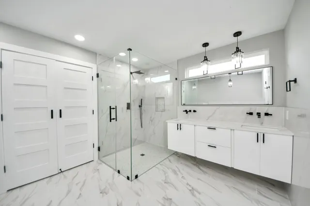 a bathroom with a glass shower door a sink and a shower