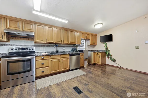 a kitchen with stainless steel appliances granite countertop a stove sink and cabinets