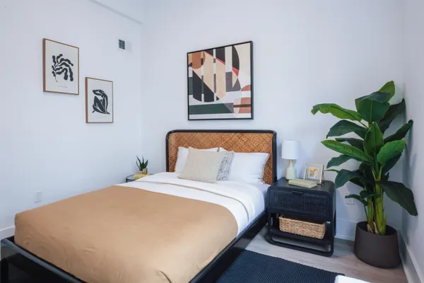a bed sitting in a bedroom next to a potted plant