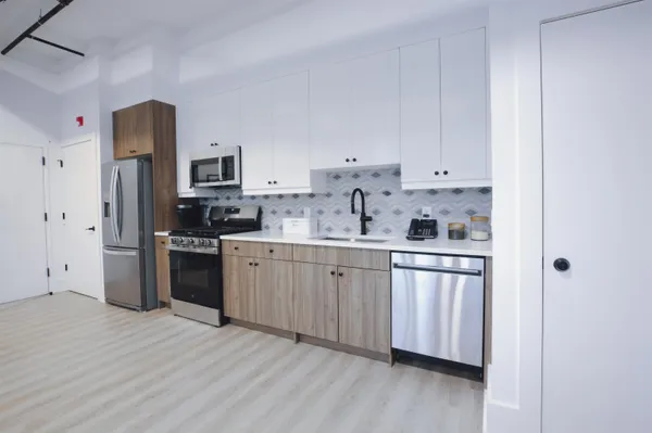 a kitchen with stainless steel appliances white cabinets a sink a stove a refrigerator and microwave