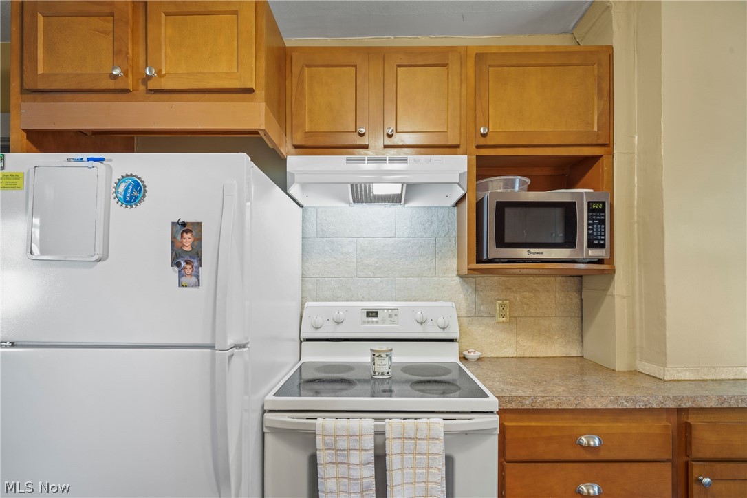 629 Clinton Street Niles, OH 44446 - Photo 11 of 50 Kitchen area featuring wood cabinetry, a white electric range with an overhead exhaust hood, and a microwave