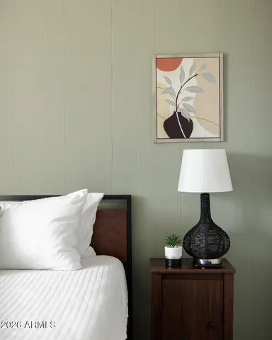 a bedroom with a bed and a lamp on the dresser