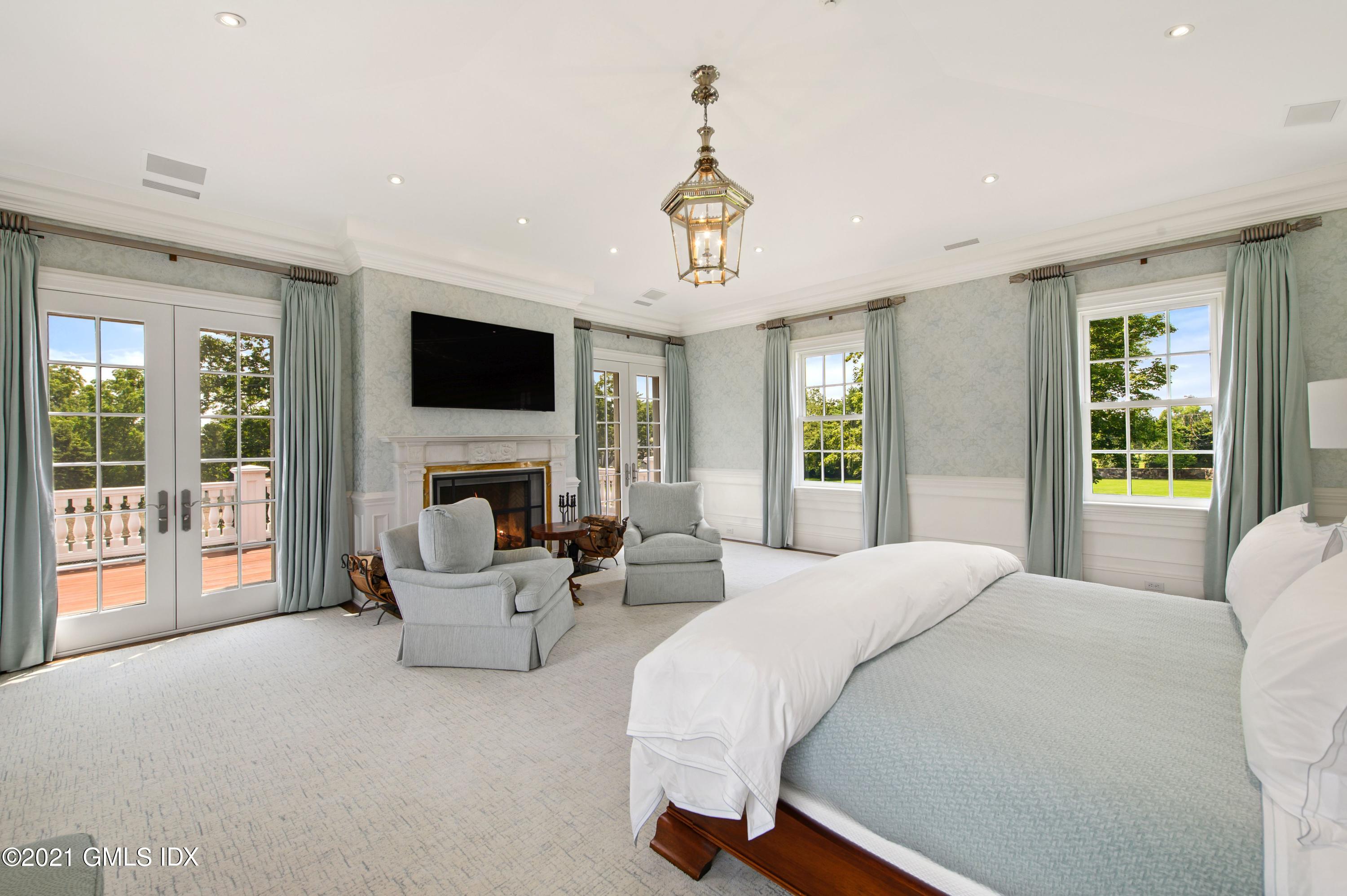 435 Round Hill Road Greenwich, CT 06831 - Photo 17 of 44 a spacious bedroom with a balcony a bed and a flat screen tv