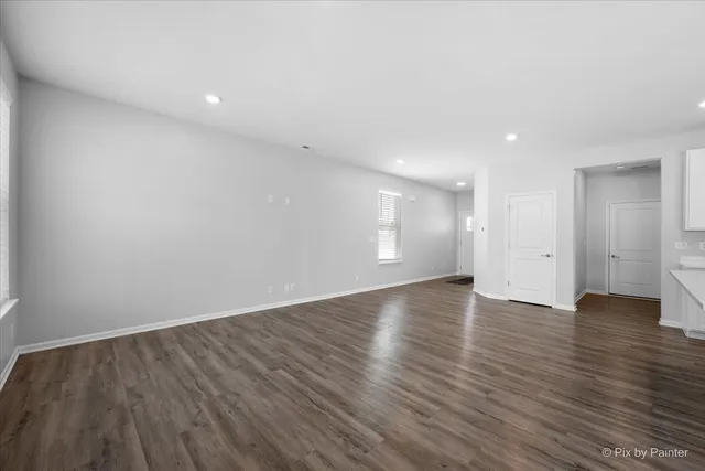 a view of an empty room with wooden floor and windows